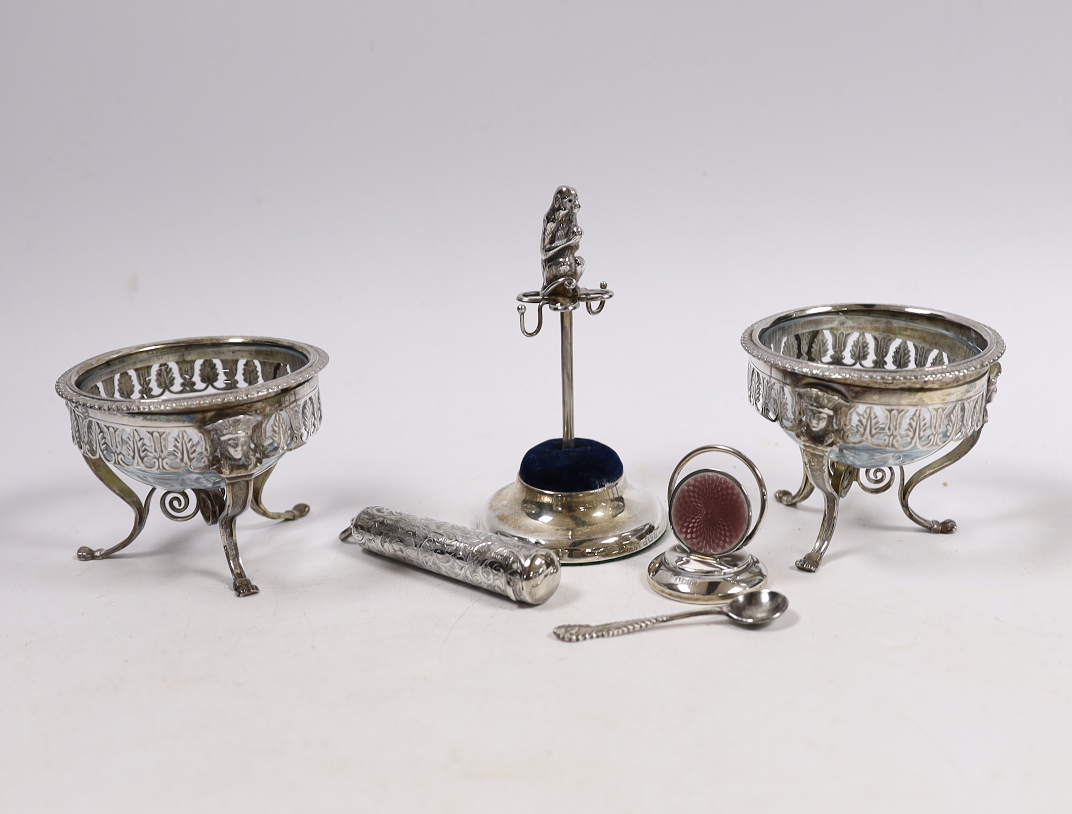 A pair of continental white metal mounted glass cauldron salts, with one associated spoon, an Edwardian silver mounted ring tree/hat pin stand, with monkey surmount, Birmingham, 1909, 10.2cm, a silver cheroot case and a